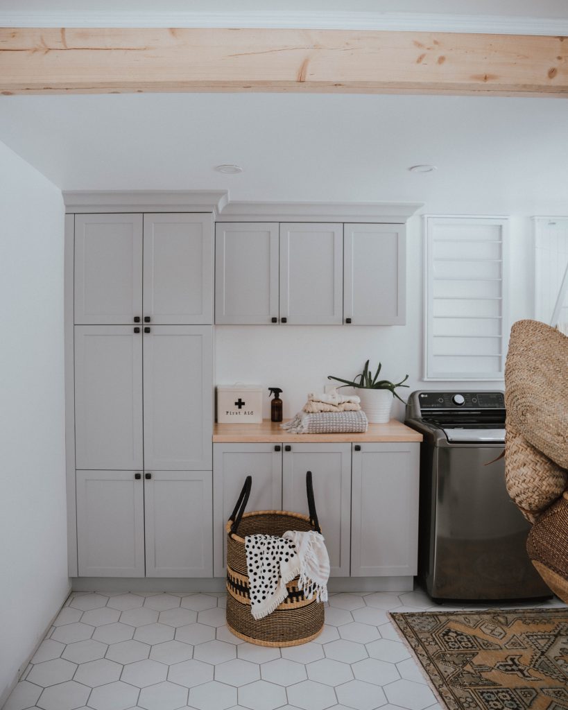 The Wild Decoelis | exposed beam in laundry room with grey cabinets