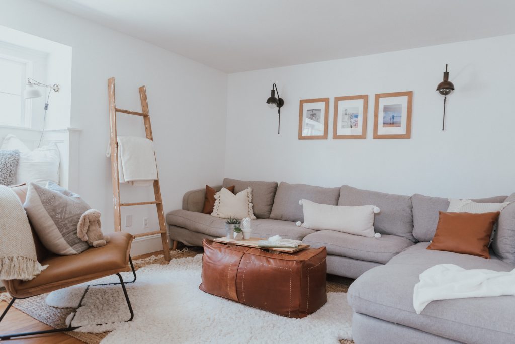 The Wild Decoelis | Our Cozy and Welcoming Family room | grey sectional, jute rug, shag sheepskin rug, leather ottoman, leather Mobilia ned chair, blanket ladder.