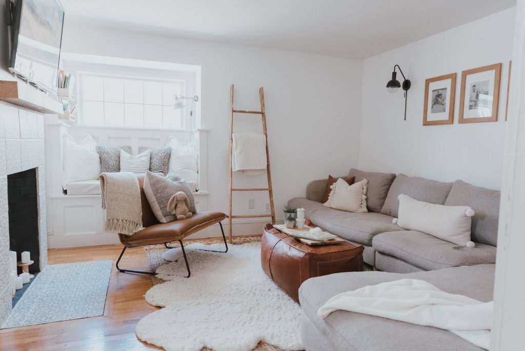 The Wild Decoelis | Our Cozy and Welcoming Family room | grey sectional, jute rug, shag sheepskin rug, leather ottoman, leather Mobilia ned chair, blanket ladder.