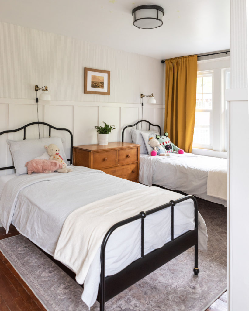 The Wild Decoelis | Our Kids Gender Neutral Shared Bedroom | yellow curtains, black accents, Ikea Bedframes, vintage art, kids room, antique dresser, board and batten wall treatment, grey ticking striped wallpaper, 