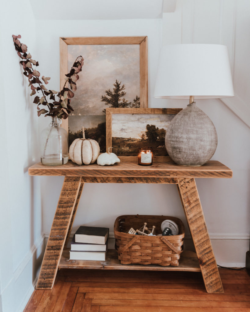 The Wild Decoelis | Fall Home Tour | DIY entry table made with reclaimed wood, Stone lamp, vintage artwork, tree branches with burgundy leaves, and white pumpkins