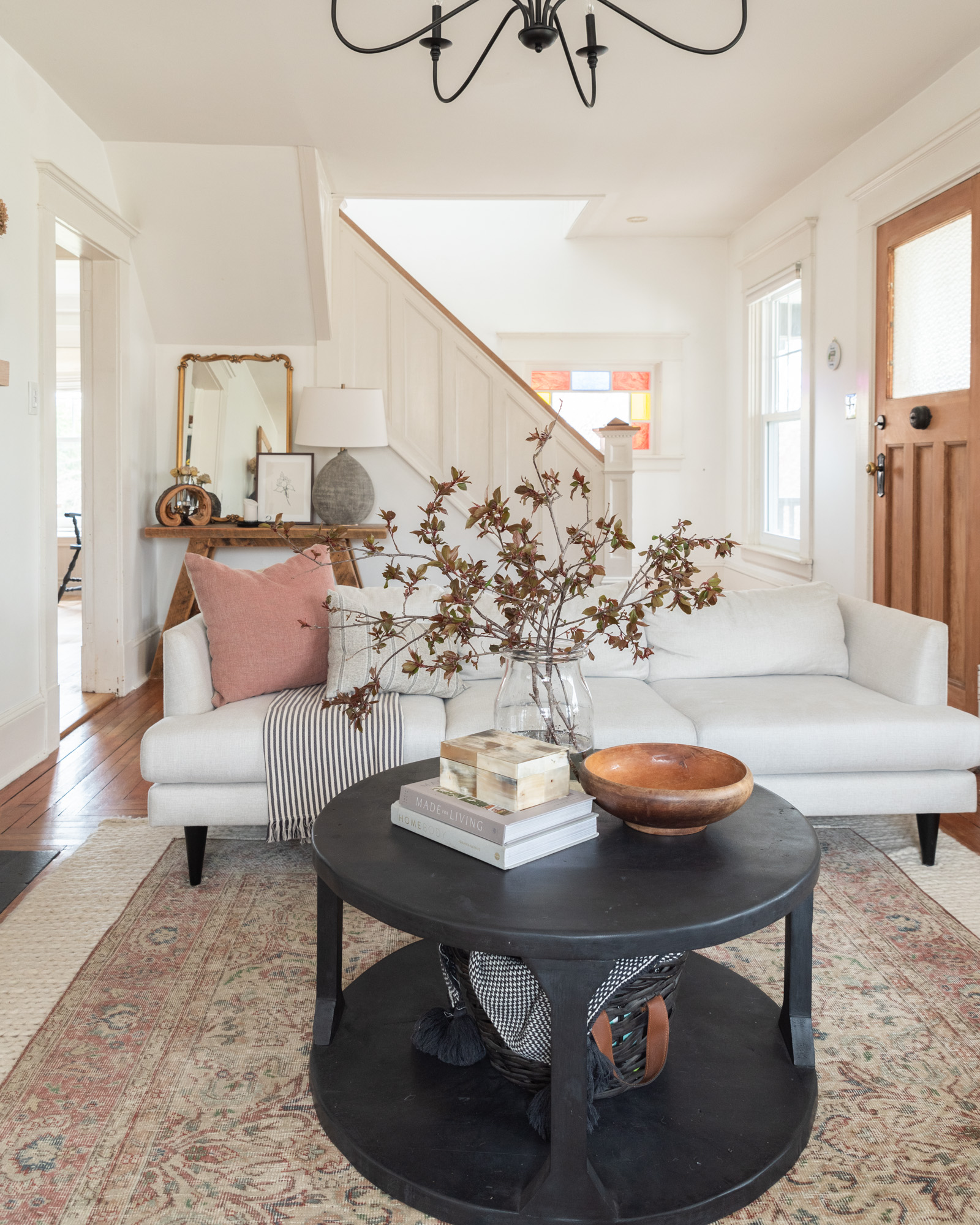 The Wild Decoelis | Four ways To Refresh Your Home For Spring | black round coffee table, cream sofa, vintage rug, flowering branches, wool rug, white craftsman living room.