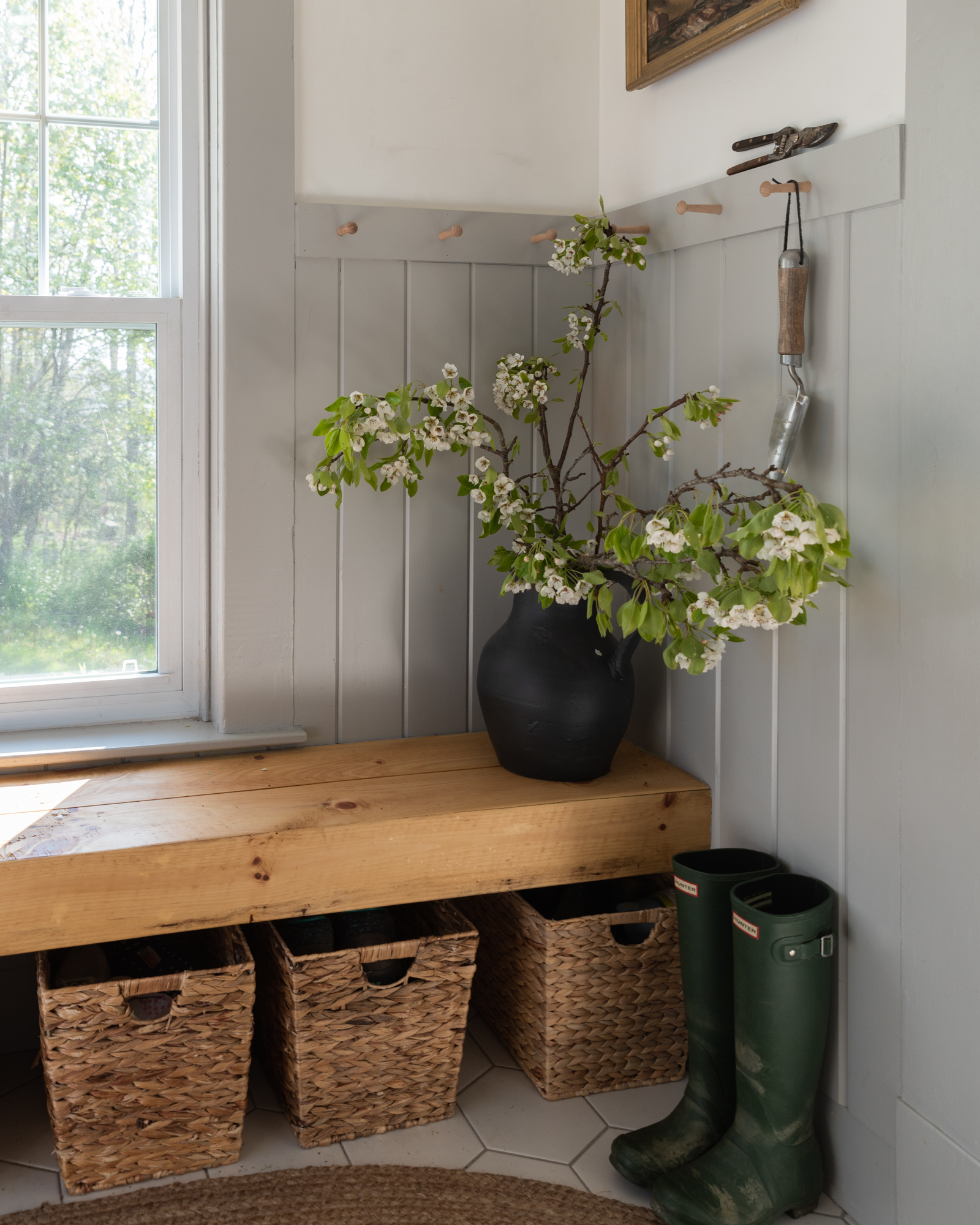 the wild decoelis | apple blossom branches in the house as decorations. Built in bench, refinished wood floors, black chairs, baskers, black vase, black chandelier, vintage art.