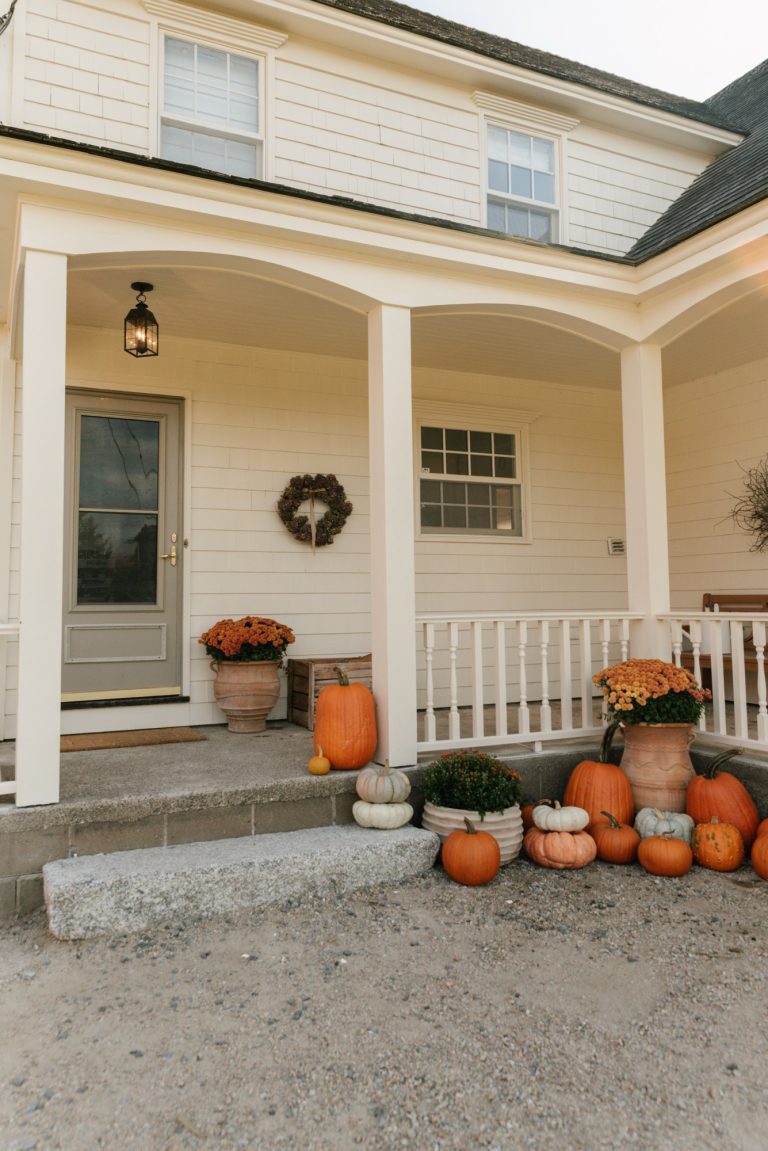 Create a timeless fall porch with classic farmhouse style. See how The Wild Decoelis styled their 1879 Nova Scotia farmhouse with simple pumpkins, mums, and the Hinkley Nantucket pendant light for a cozy, welcoming autumn look.
