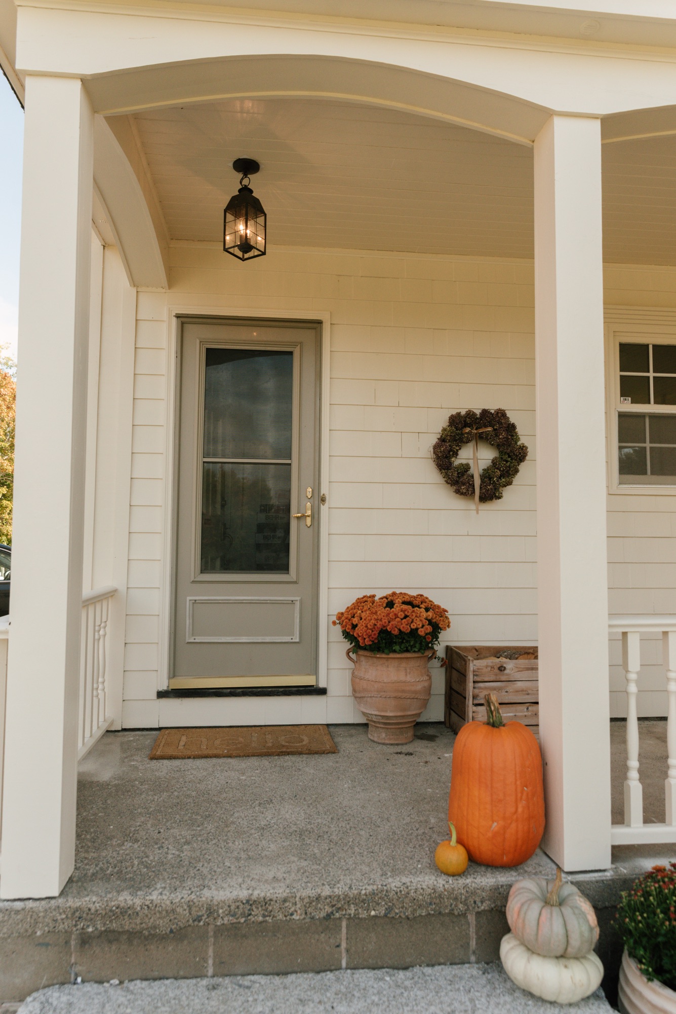 Cluster of heirloom pumpkins and terracotta planters with mums on farmhouse porch steps.