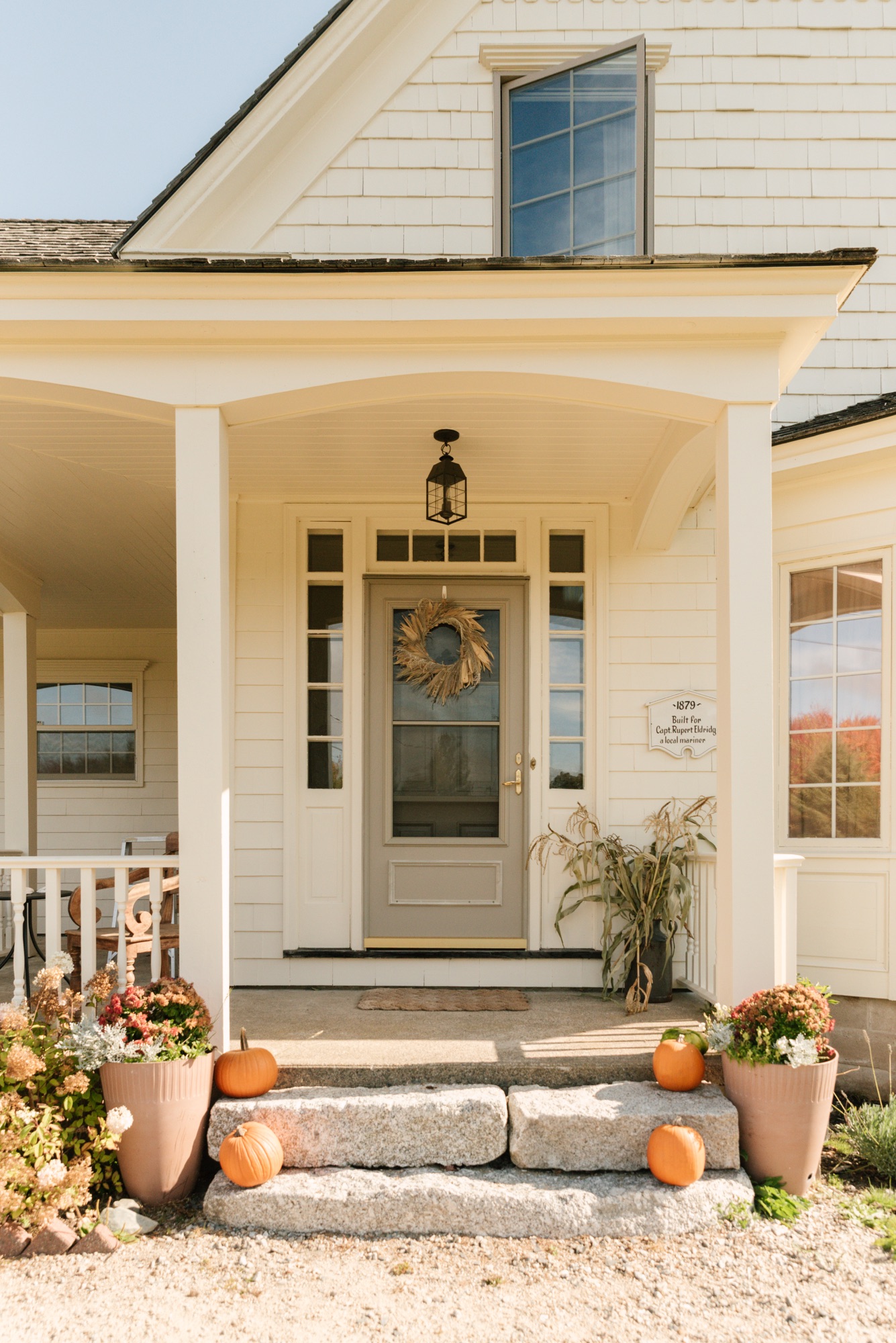 Nova Scotia farmhouse porch decorated for fall with pumpkins, mums, and Hinkley Nantucket pendant light.