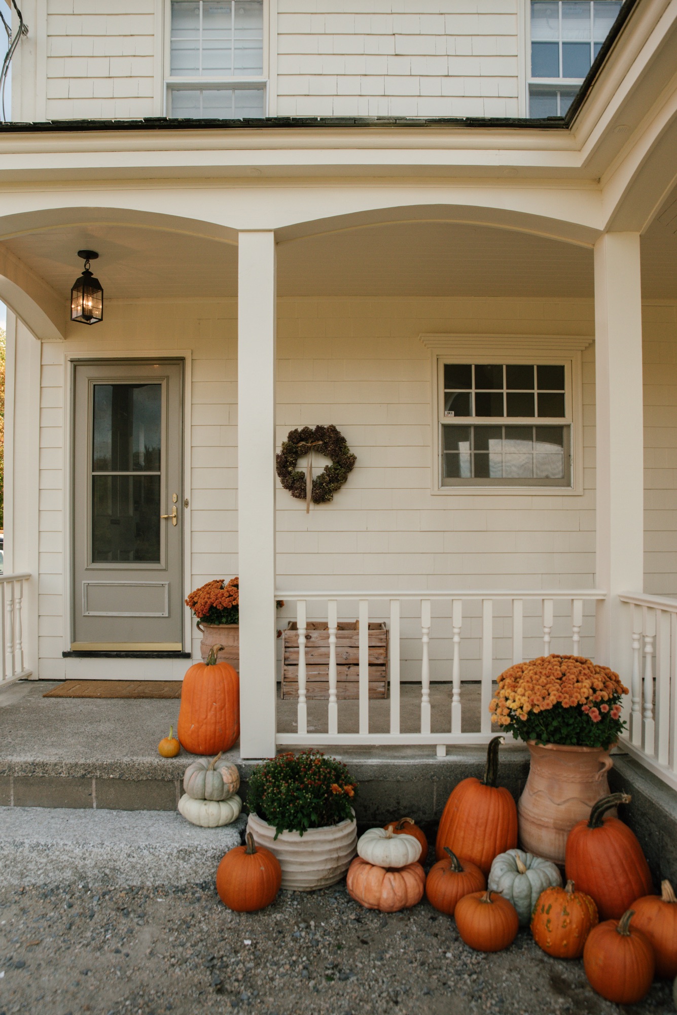 Front entrance of historic Nova Scotia farmhouse with Hinkley Nantucket pendant, pumpkins, and cornstalks for fall.